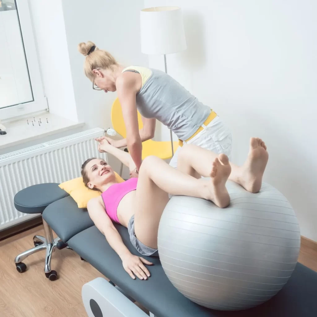 Woman helping a patient using an exercise ball for therapy