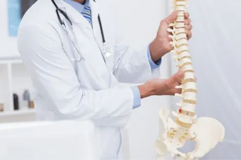 Chiropractor pointing to spine model for patient