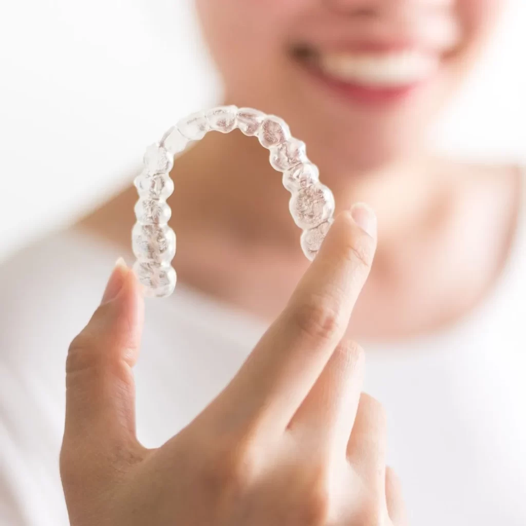 Hand displaying an Invisalign clear aligner