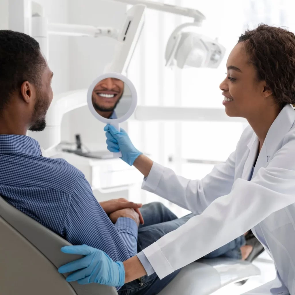 Dentist assisting patient with a teeth crown using a mirror