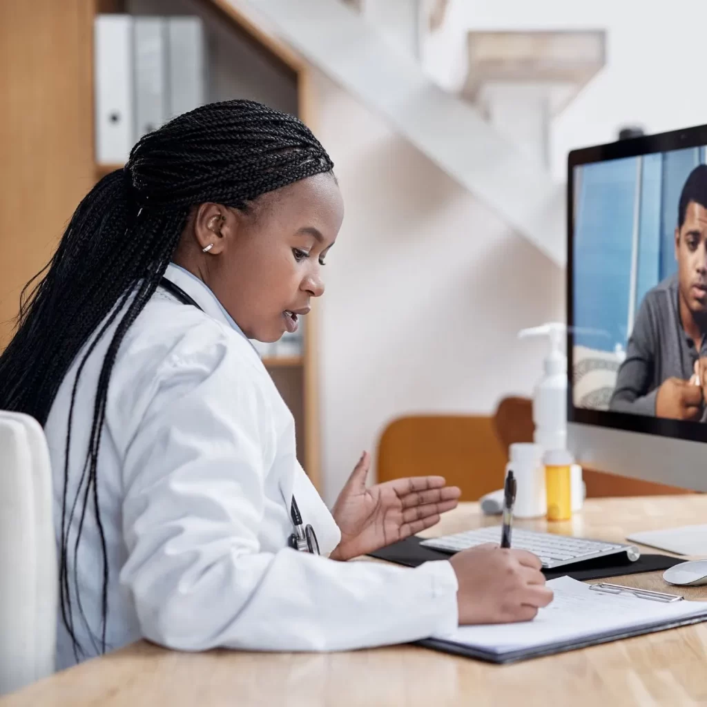 A doctor conducting a virtual appointment with a patient and documenting a medical record.