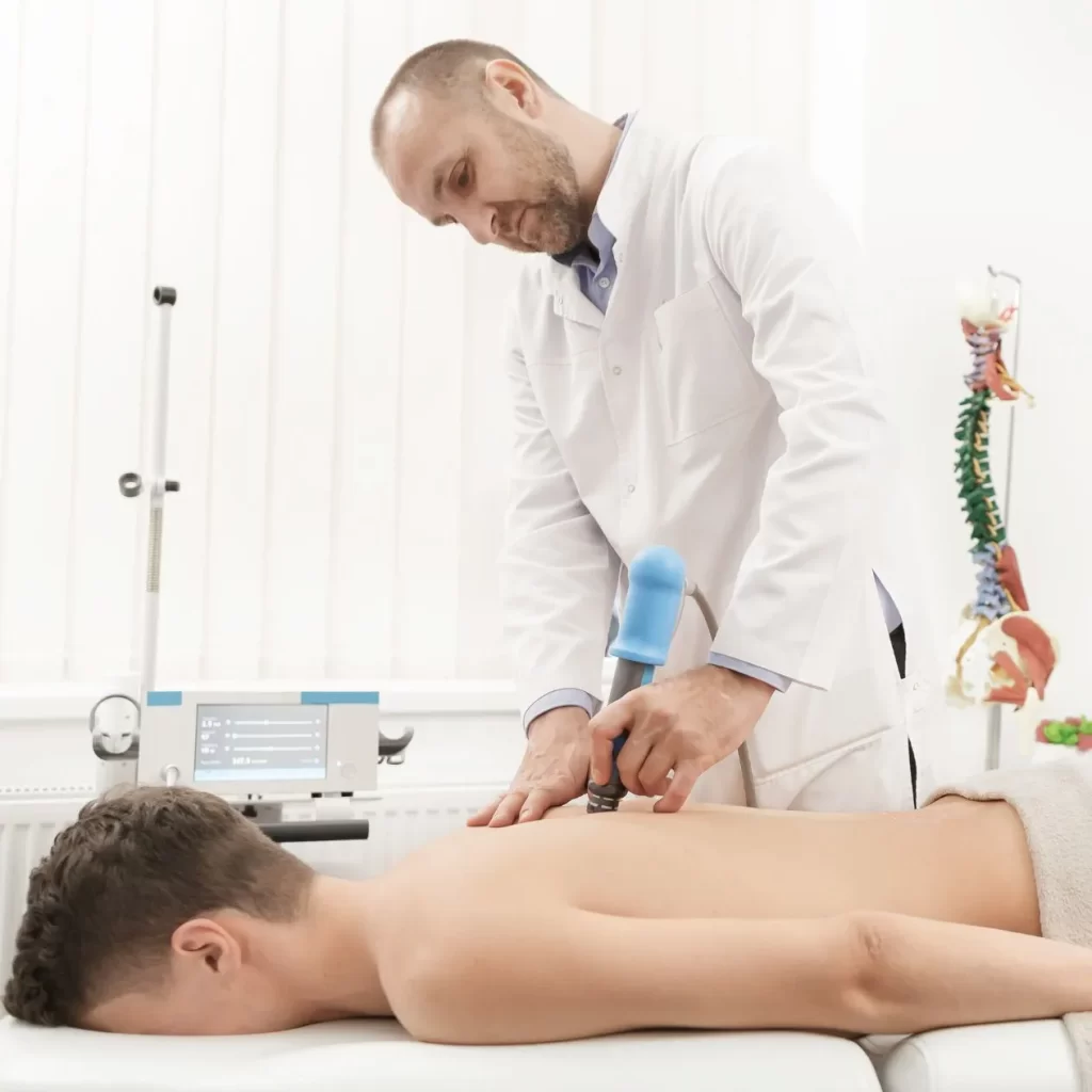 Chiropractor doing shockwave therapy on patient