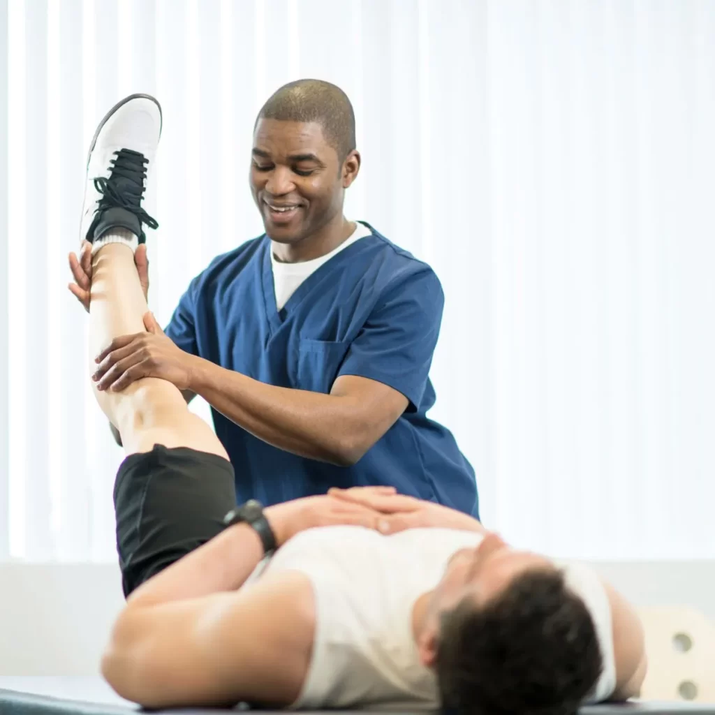 Physiotherapist moving a man's leg from sports injury
