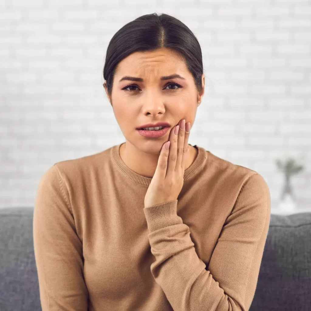 Woman holding mouth while recovering from wisdom teeth removal