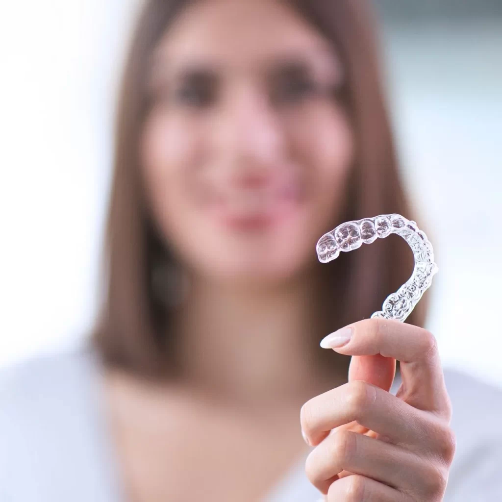 Smiling woman holding Invisalign aligners