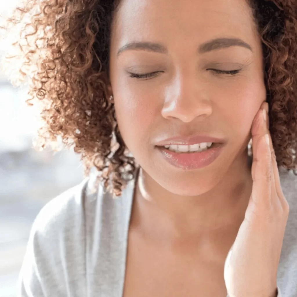 Woman holding mouth from sore wisdom tooth