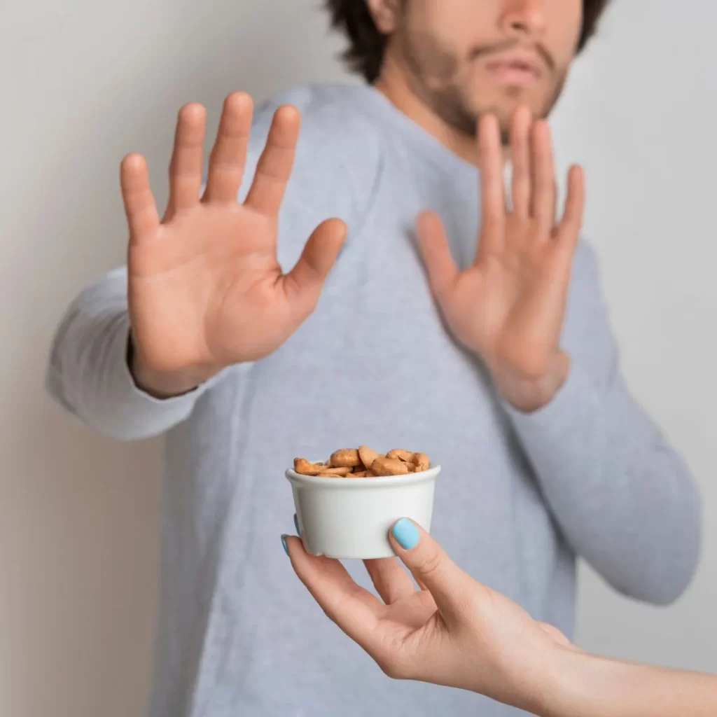 Man frowning at peanuts from peanut allergy