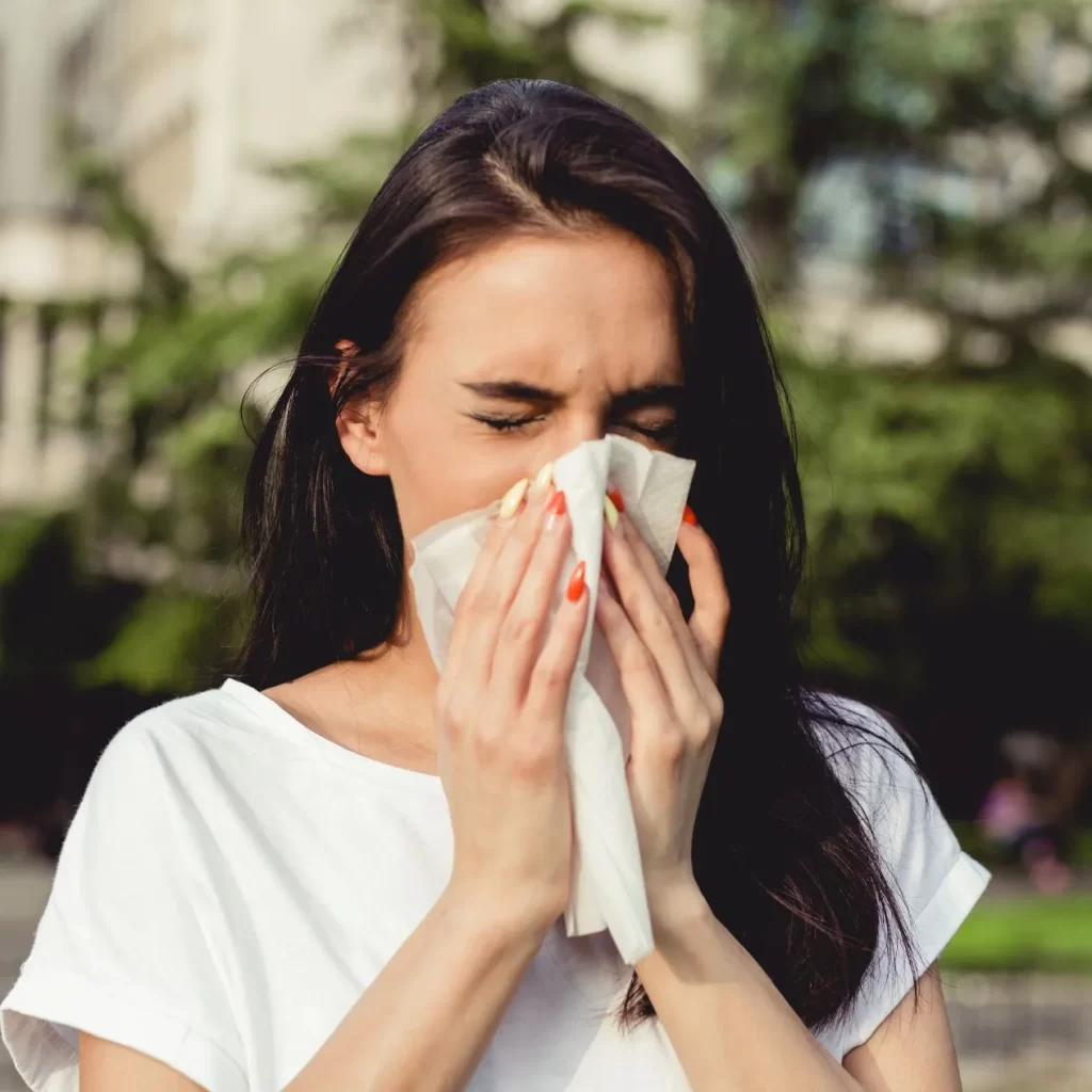 Woman experiencing allergies and blowing her nose