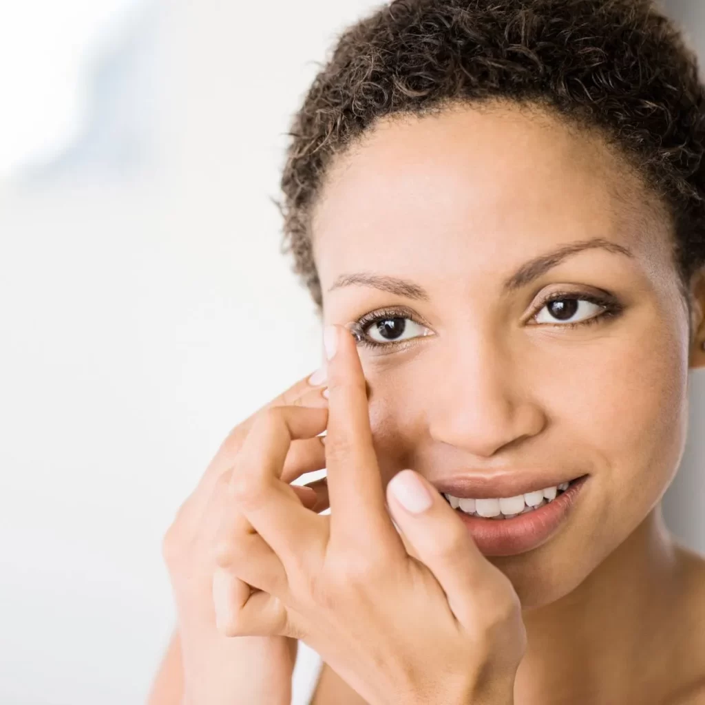 woman smiling and applying contact lenses
