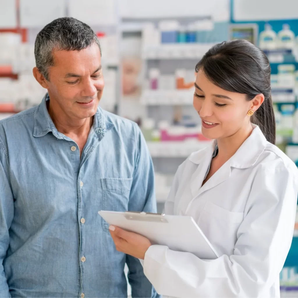 smiling pharmacist writing prescription with patient