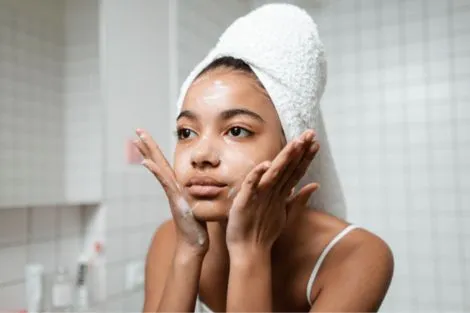 woman with acne scars washing her face