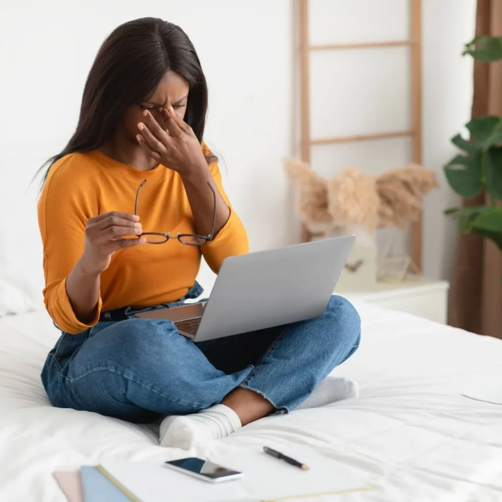 woman with dry eyes rubbing her eyes at laptop