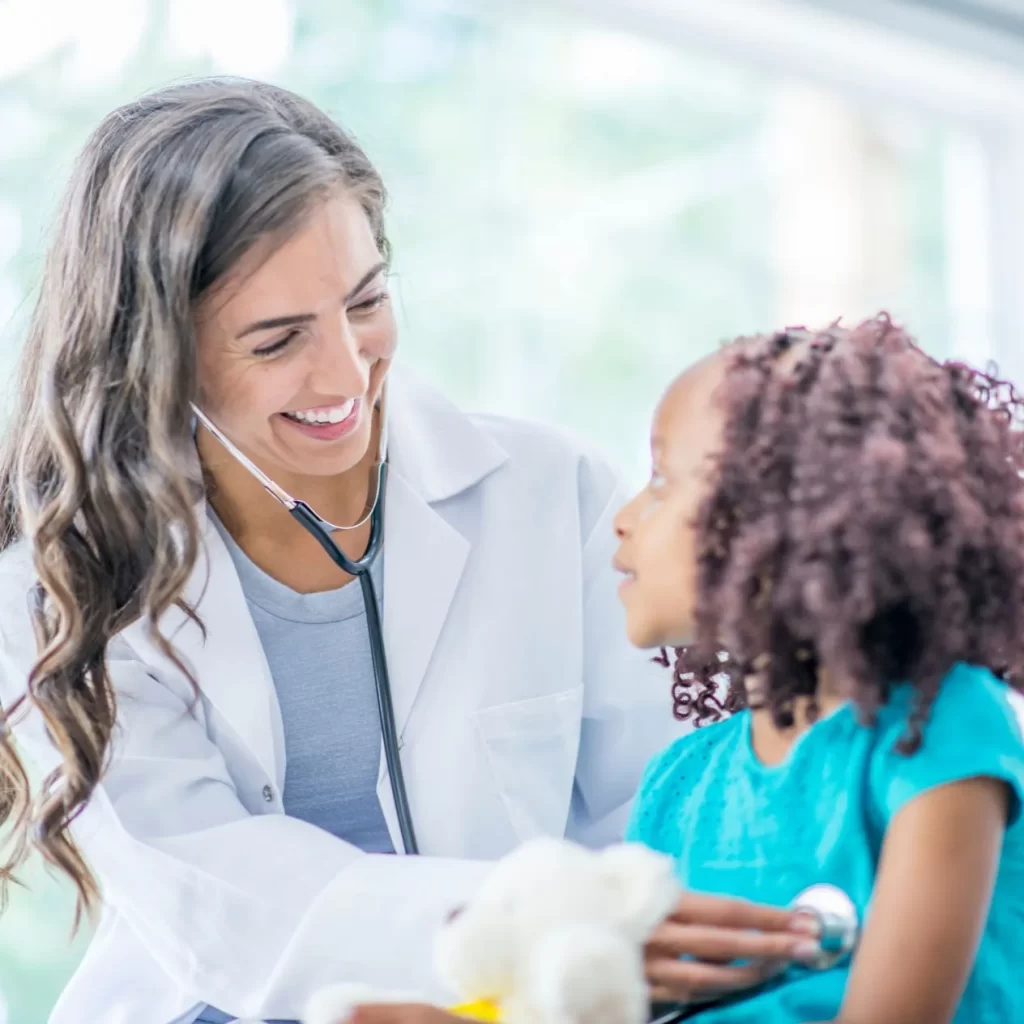 Friendly pediatrician treating a young girl at medical clinic