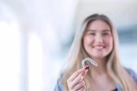 Woman showing Invisalign aligners to correct bite
