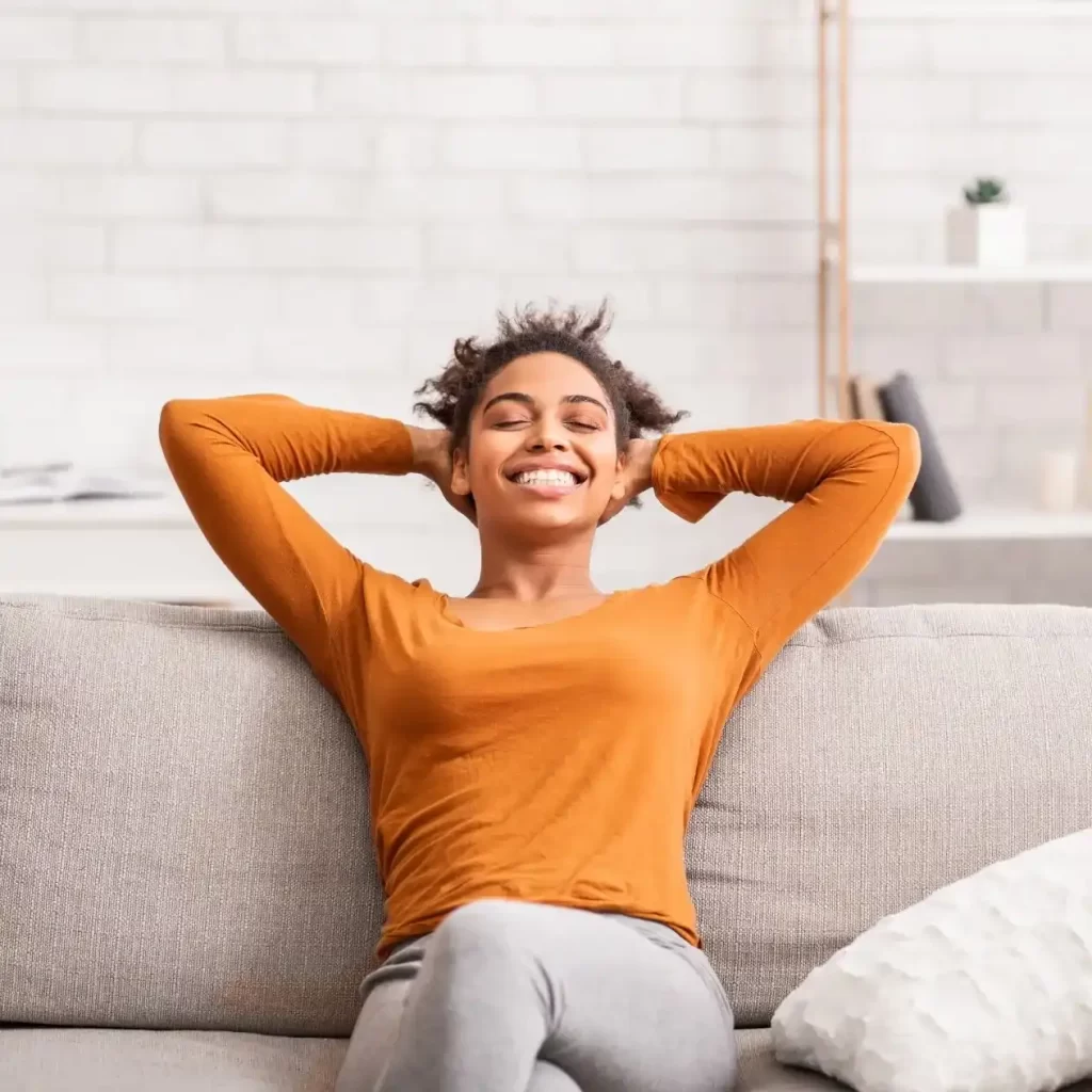 woman smiling on a couch with balanced hormones