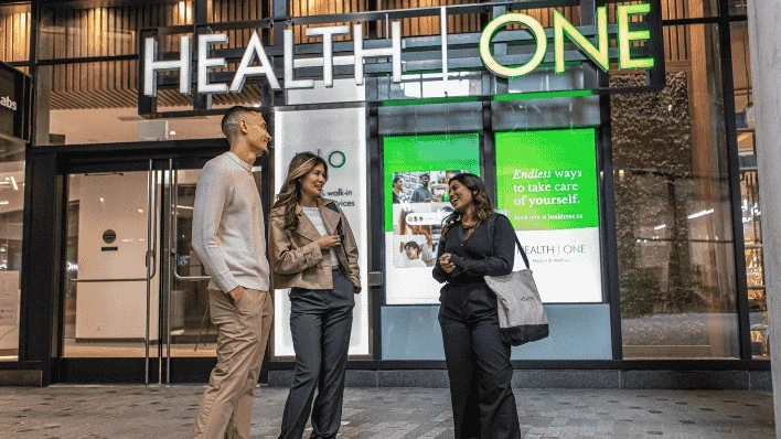 healthone at the well front entrance with staff members posing